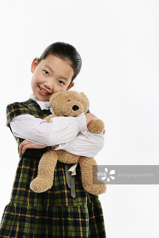 女孩(12-13)抱着泰迪熊，微笑着，肖像，特写图片素材