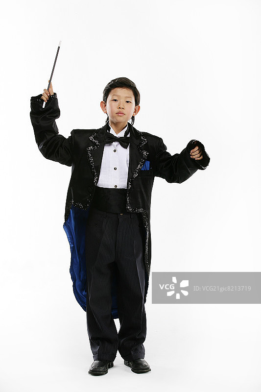 男孩(12-13岁)身穿魔术师服装，手持魔术棒，面带微笑图片素材