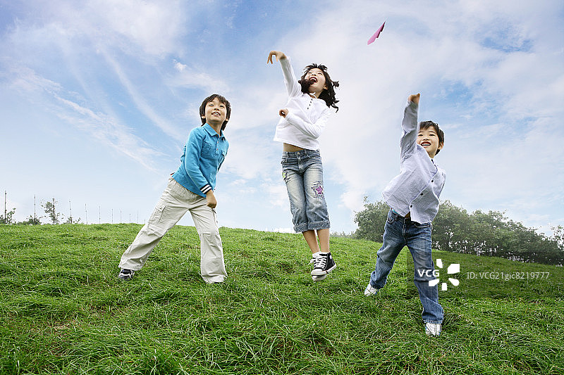 孩子们(6-11岁)在草地上扔纸飞机图片素材