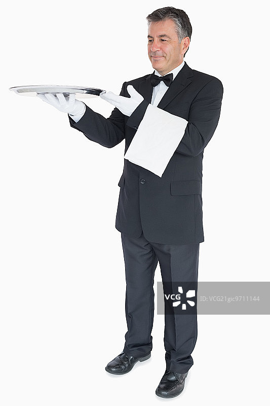 微笑的侍者举着白色背景上的空银托盘图片素材