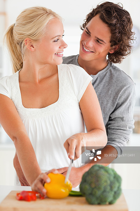 一对微笑的夫妇在厨房里切辣椒图片素材