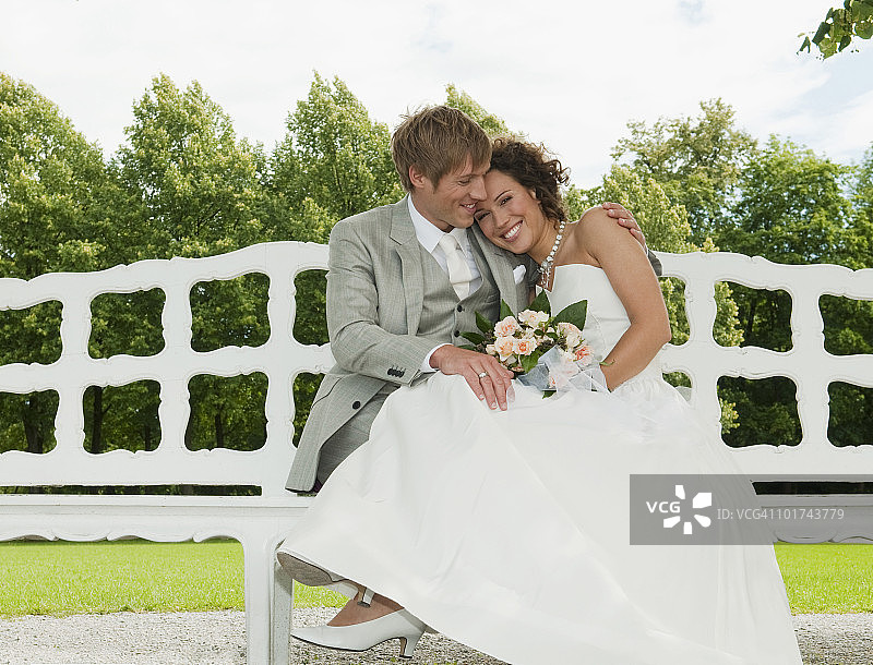德国，巴伐利亚，新婚夫妇坐在长椅上，在户外，微笑着，画像图片素材
