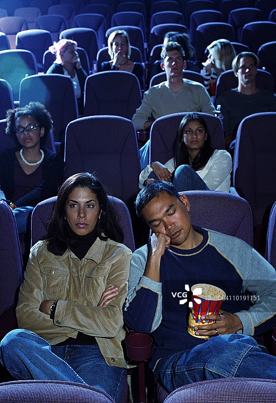 一对无聊的情侣在电影院，男人睡着了图片素材