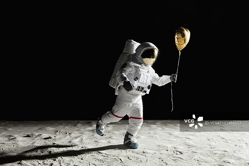 一个宇航员在月球上拿着一个心形的氦气球图片素材