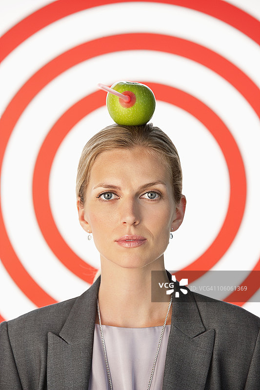 女商人头顶苹果，正中靶心图片素材