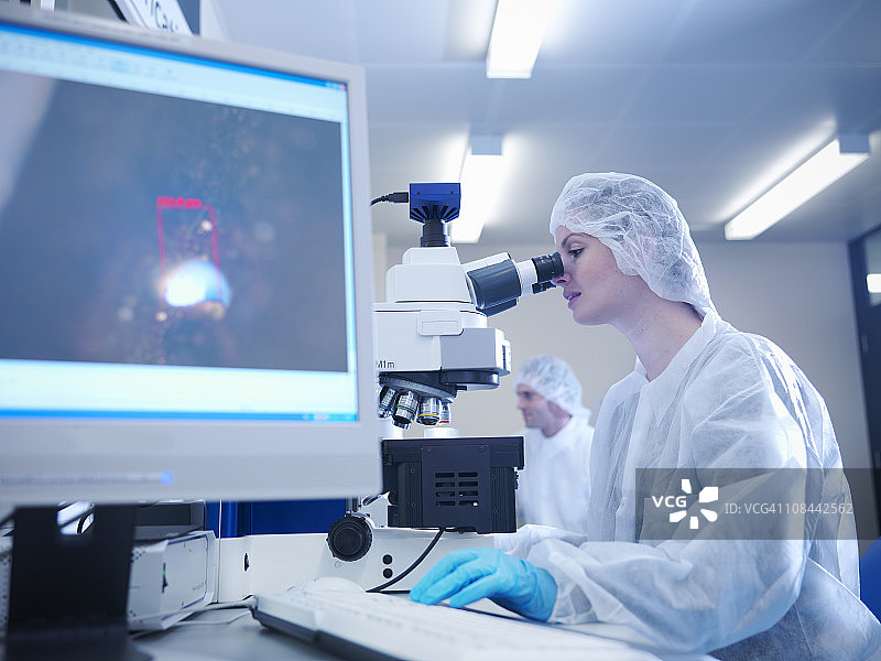 穿着防护服的女科学家在激光实验室使用显微镜图片素材