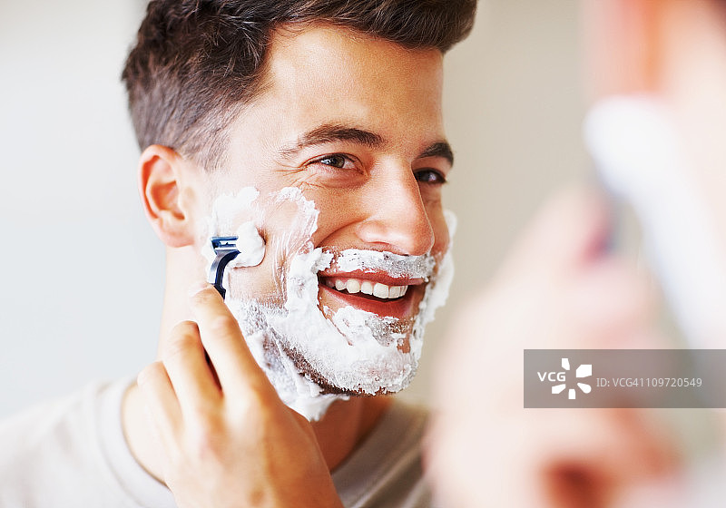 快乐的中年男子用剃须刀刮胡子图片素材