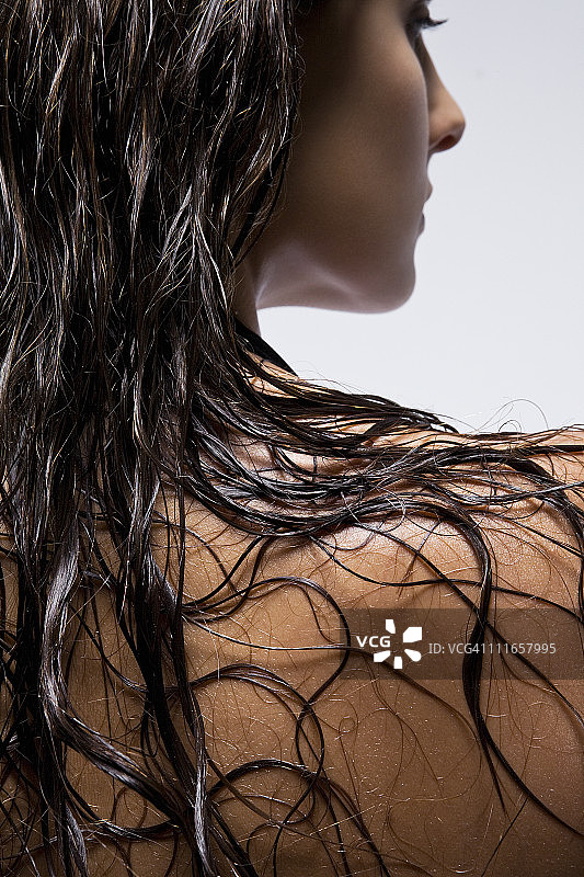 年轻女子，湿漉漉的头发披在肩上。图片素材