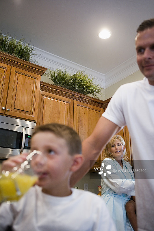 男孩喝果汁，背景是父母图片素材