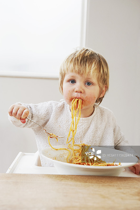 凌乱的小男孩在吃意大利面图片素材