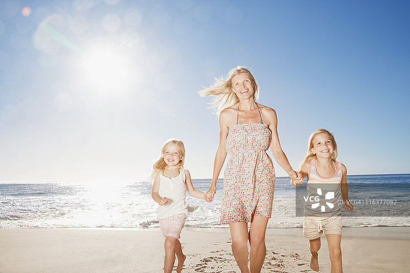 母亲和女儿在海滩上跑步图片素材
