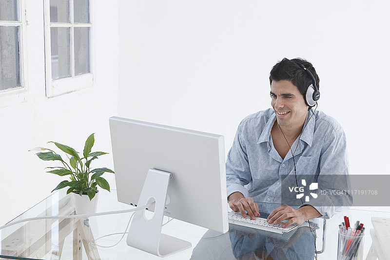 男人戴着耳机在电脑前图片素材