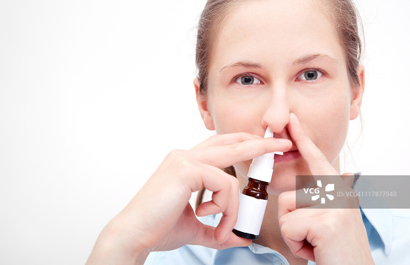 妇女使用喷雾剂，并保持其他鼻孔关闭。图片素材