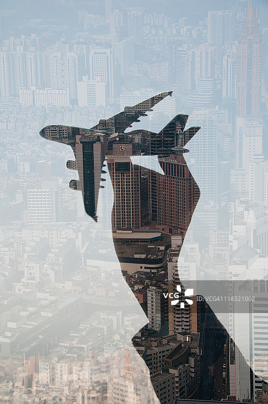 手持式飞机和城市的双重曝光图片素材