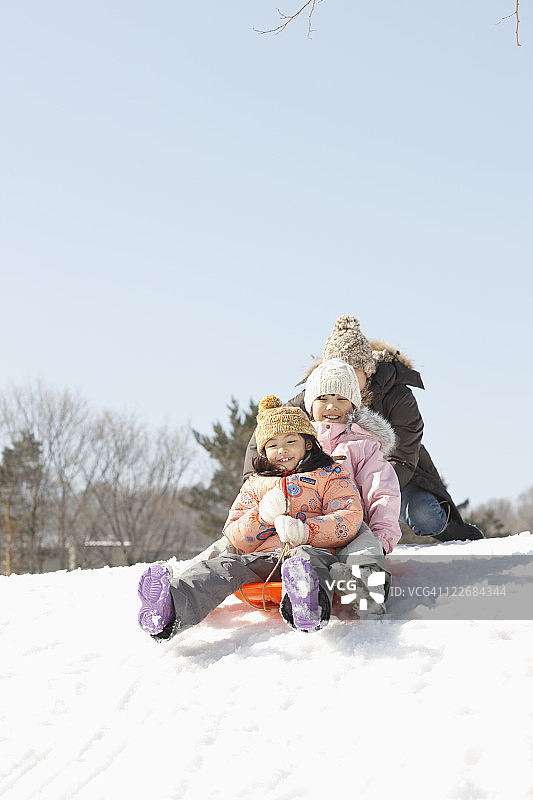 父亲和孩子们在玩雪橇图片素材