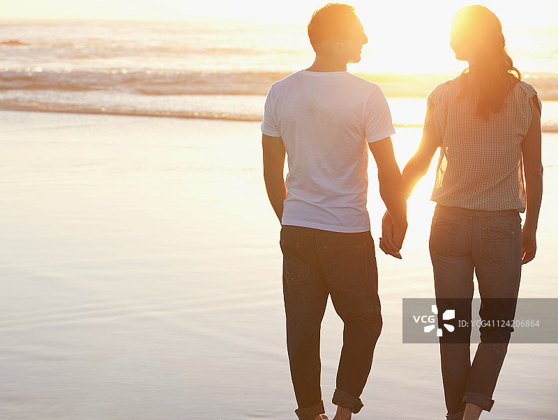 后视图的一个浪漫的夫妇走在海滩手牵手图片素材