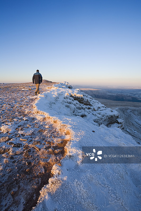 白种人行走者(29岁)在玉米杜山顶的日出在冬天。布雷肯灯塔国家公园。波伊斯。威尔士。英国。图片素材