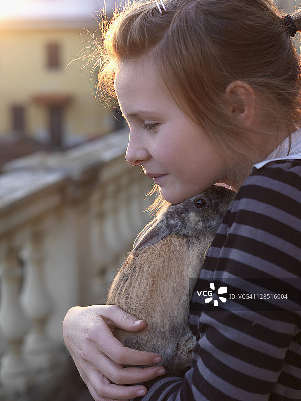 意大利，少女在阳台上拥抱宠物兔子图片素材