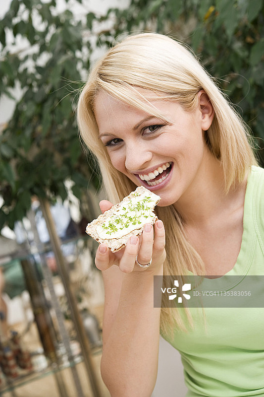 快乐的年轻女子吃着脆面包图片素材