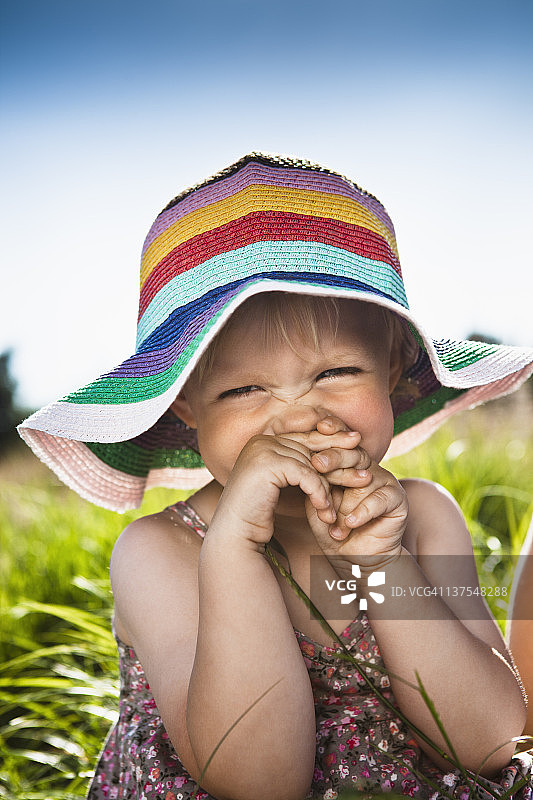 在草地上戴太阳帽的蹒跚学步的女孩图片素材