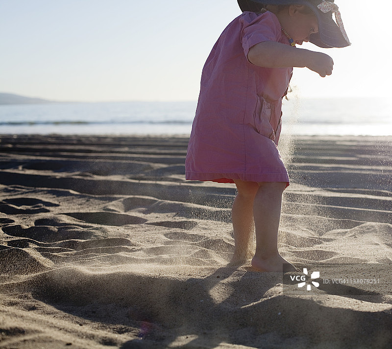 小女孩在沙滩上玩跳沙游戏图片素材