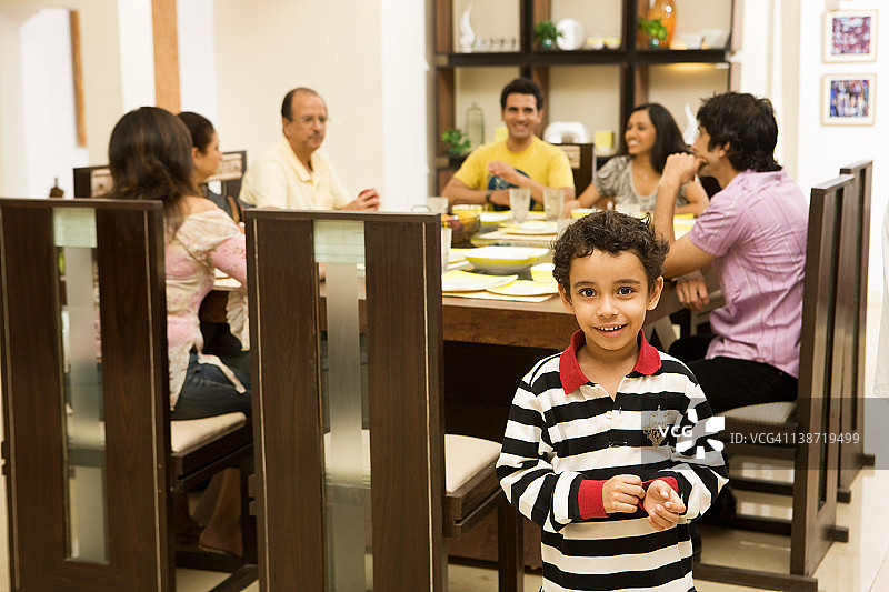 男孩面带微笑，背景家庭在餐厅里图片素材