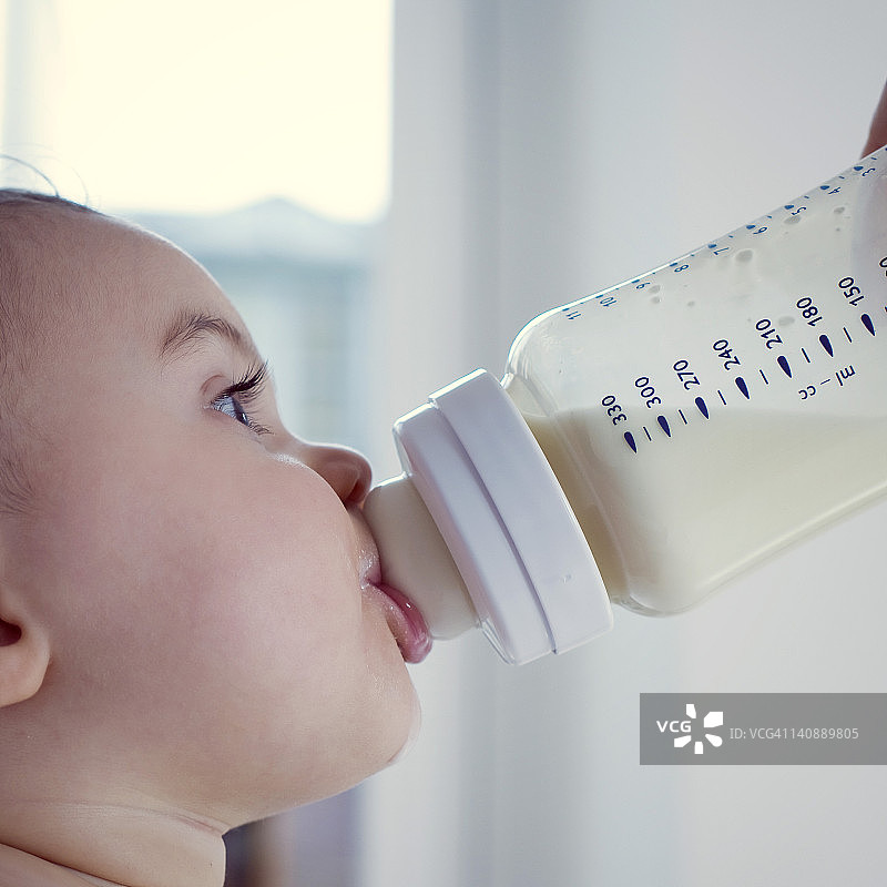婴儿从瓶中喝牛奶，侧面观图片素材