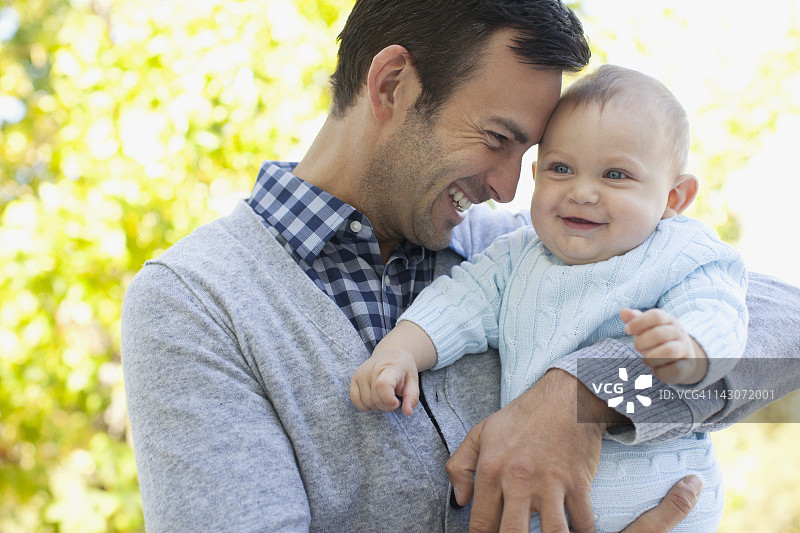 微笑的父亲抱着婴儿在户外图片素材