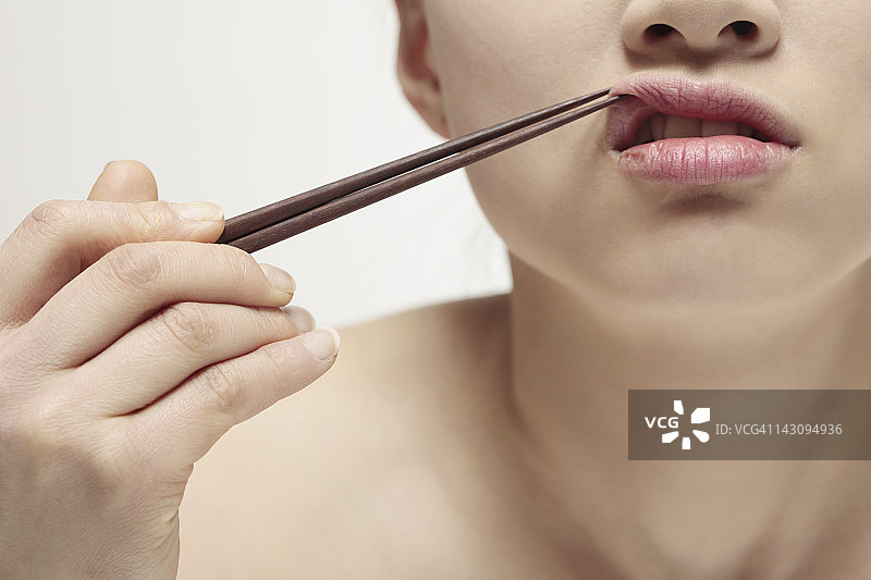 女人用筷子夹嘴唇，特写图片素材
