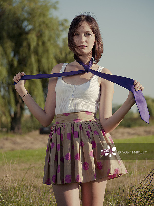 一个年轻女人拿着她的紫色领带的肖像图片素材