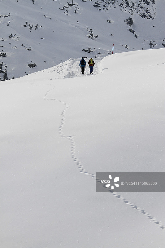 两个人在远处的雪地徒步旅行图片素材