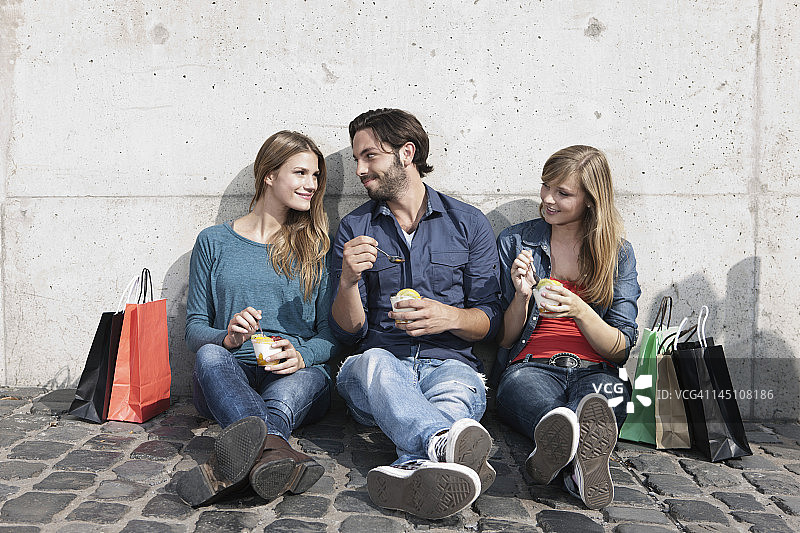 德国，科隆，年轻男女拿着冰淇淋和购物袋，面带微笑图片素材