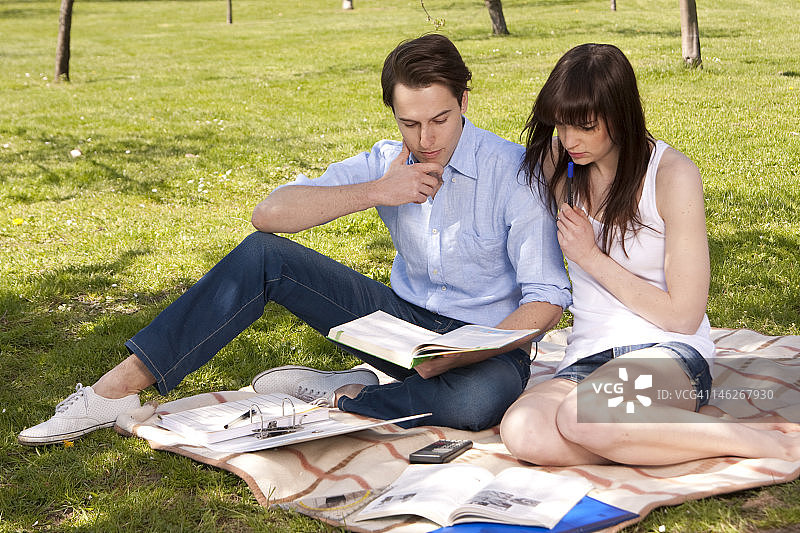 一对年轻夫妇坐在铺着纸的毯子上图片素材