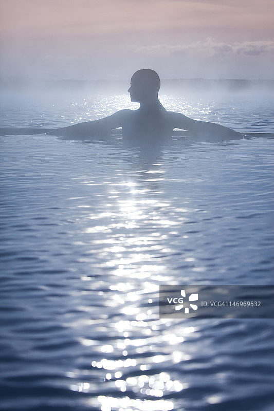 日落时分，雾气氤氲的温泉中女孩的剪影图片素材