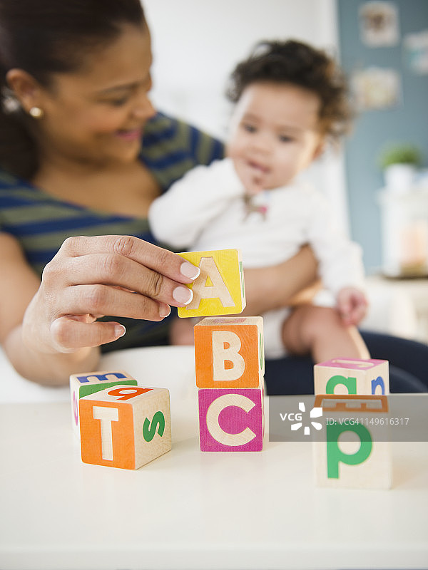 混合种族的母亲和婴儿玩字母积木图片素材