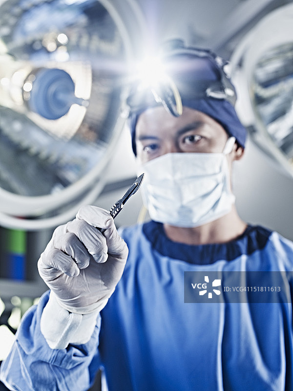 外科医生在手术灯光下拿着手术刀图片素材