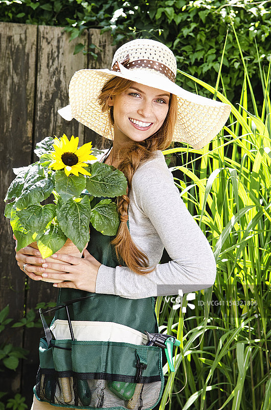 微笑的年轻女子与向日葵在花园里图片素材