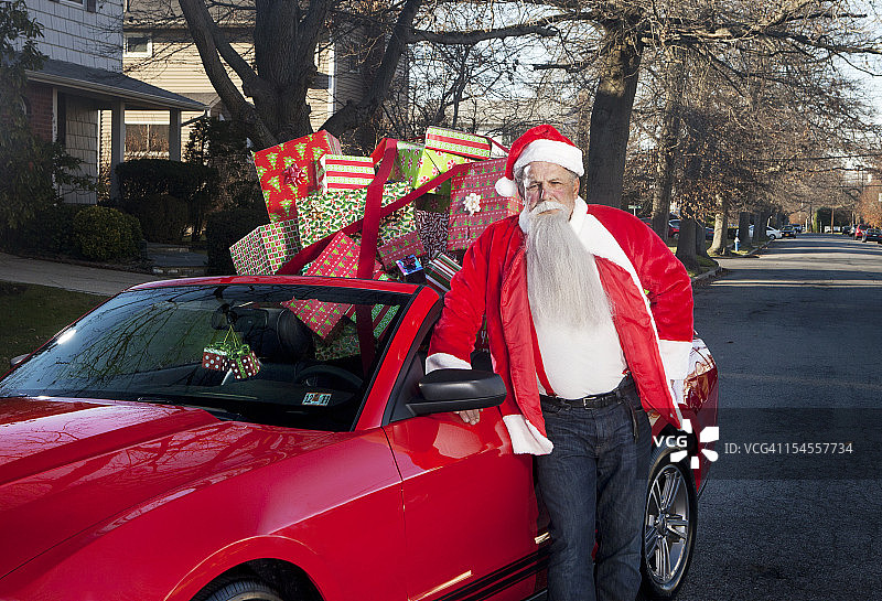 圣诞老人倚着装满礼物的敞篷车图片素材