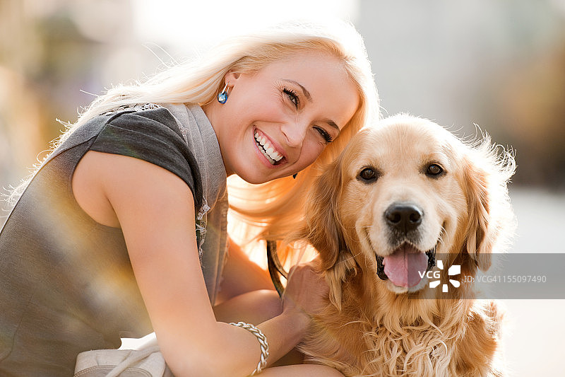 微笑的金发女性和她的狗。图片素材