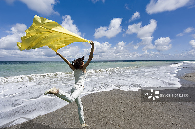 自由-女人在风中拿着黄色围巾跳海边图片素材
