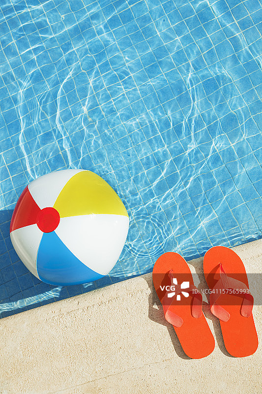 游泳池夏天的乐趣与浮动沙滩球，人字拖图片素材