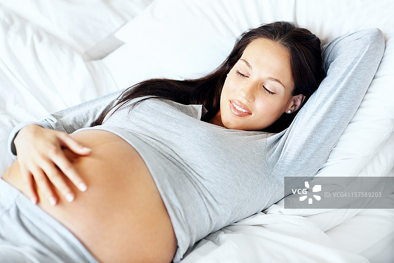 年轻孕妇看着自己的肚子图片素材