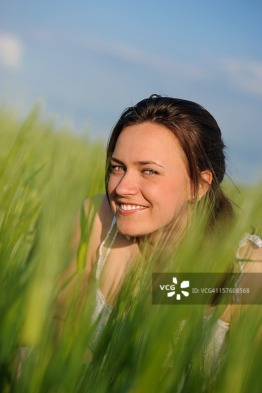 快乐的年轻女子躲在绿色的麦田里图片素材