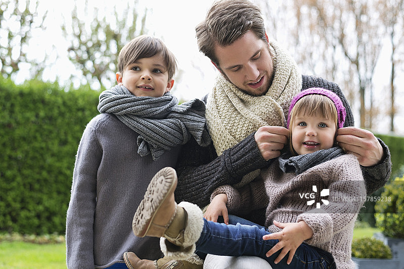 一个男人和他的儿子和女儿穿着暖和的衣服在公园里图片素材