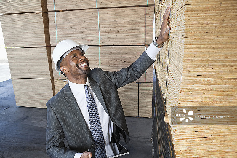 快乐的非裔美国男性承包商检查木板，同时拿着平板电脑图片素材
