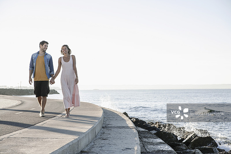 西班牙，一对中年夫妇沿着海岸散步图片素材