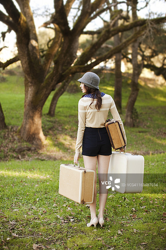 树旁的女人拿着老式行李箱图片素材