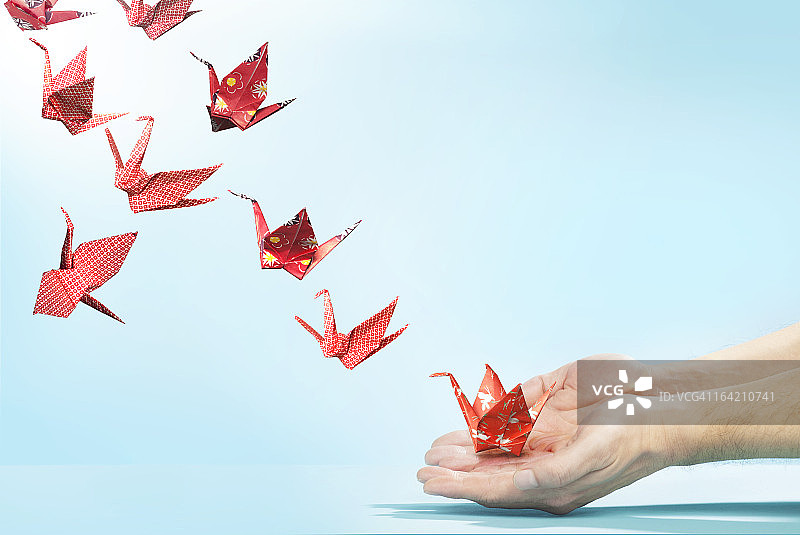 红色的纸鹤从手中飞开图片素材