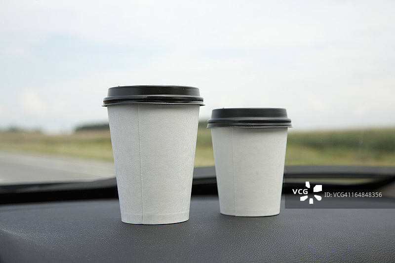 两杯一次性咖啡放在汽车仪表盘上图片素材