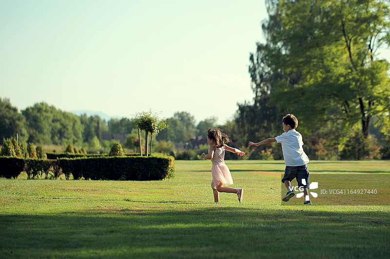 男孩和女孩在公园里快乐地奔跑。图片素材